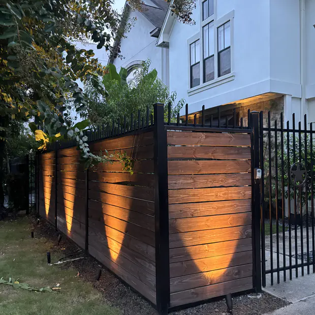 Timber fence and gate grazed with low-voltage uplighting at dusk