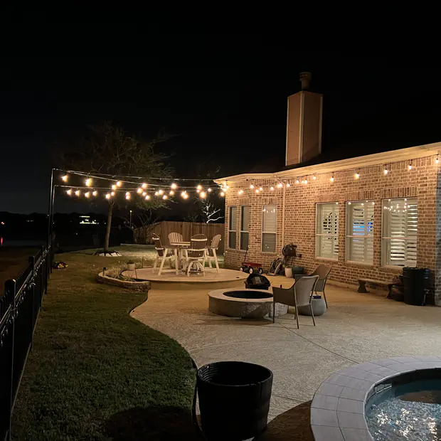 Bistro lighting over a pool deck and covered patio at night