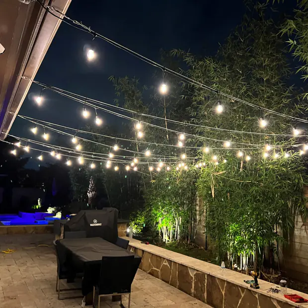 Patio lit with overhead string lights and coloured accent lighting