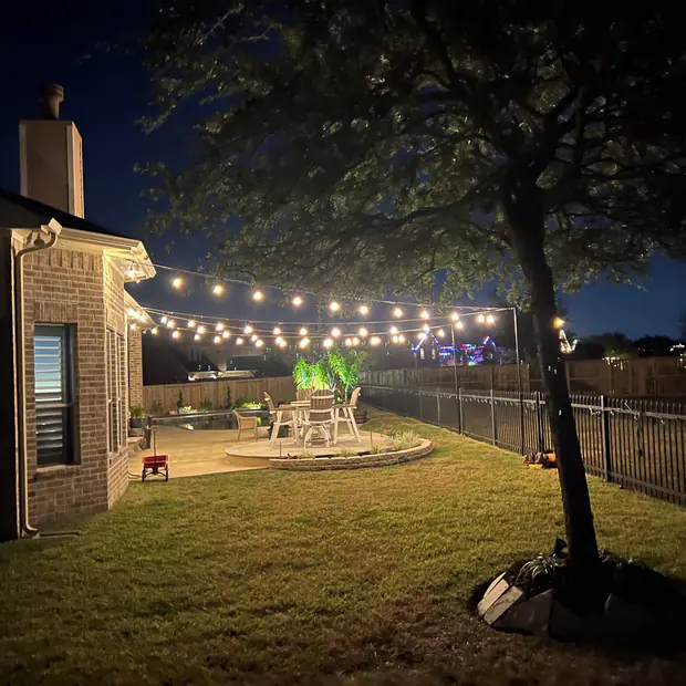 Backyard string lighting running from the house out across the garden