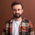 portrait of handsome attractive stylish bearded man on brown background isolated in vintage flannel checkered shirt smiling